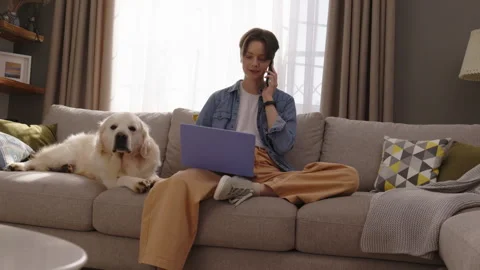 Young Professional Working on Laptop and Talking on Phone While Golden Retriever Stock Footage 280501997