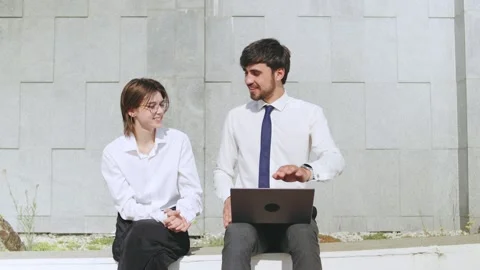 Young professionals engage in conversation while working outdoors in a modern Stock Footage 316045978