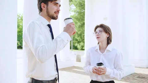 Young professionals engage in conversation while enjoying coffee outside a Stock Footage 316051241