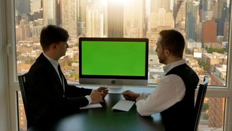 Young professionals looking at green screen covered computer monitor meeting in Stock Photos