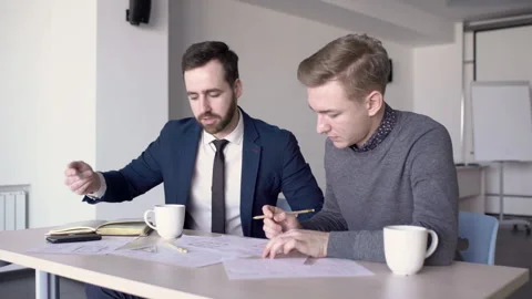Young professionals work on blueprint at table in modern office. Stock Footage 85625719