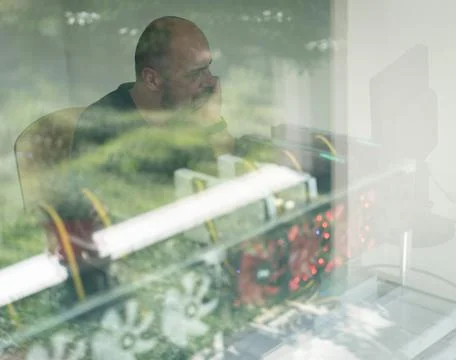 Young programmer adjusting cryptocurrency mining rig to optimal operational Foto stock