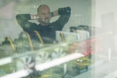 Young programmer adjusting cryptocurrency mining rig to optimal operational Foto stock