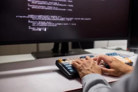 A young programmer codes intently in a dark setting, immersed in his work and Stockfoto's