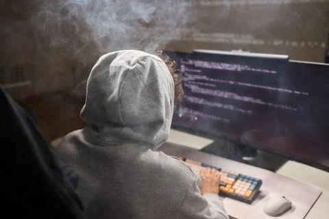 A young programmer codes intently in a dark setting, immersed in his work and Stockfoto's