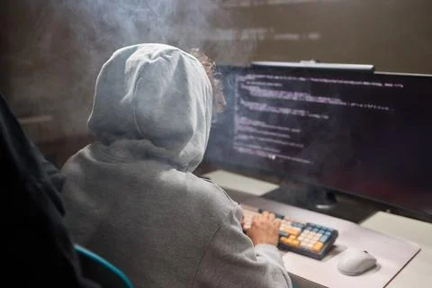 A young programmer codes intently in a dark setting, immersed in his work and Stock Photos