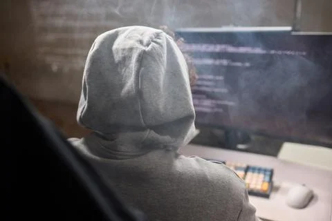 A young programmer codes intently in a dark setting, immersed in his work and Stock Photos