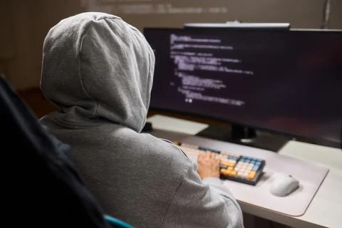 A young programmer codes intently in a dark setting, immersed in his work and 库存照片
