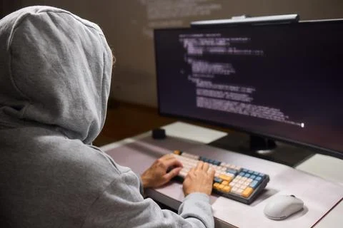 A young programmer codes intently in a dark setting, immersed in his work and Stockfoto's