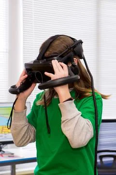 Young programmer girl in a virtual reality helmet. Stock Photos