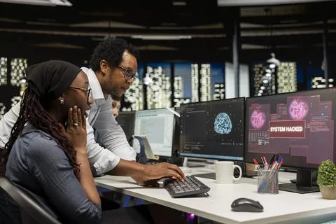 Young programmer in office requests help from team leader to fix hacking attempt Stock-Fotos