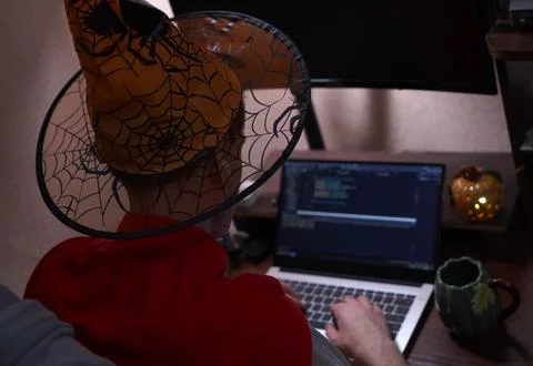 Young programmer in orange autumn wizard hat and red sweater on shoulders w.. Foto stock