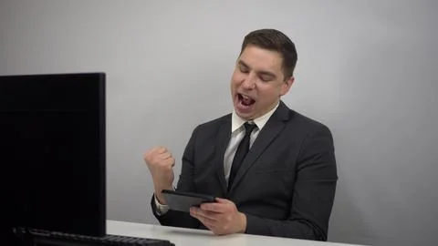 A young programmer plays a game on the phone. Businessman plays at work in the Stock Photos