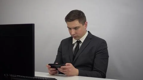 A young programmer plays a game on the phone. Businessman plays at work in the Stock Photos