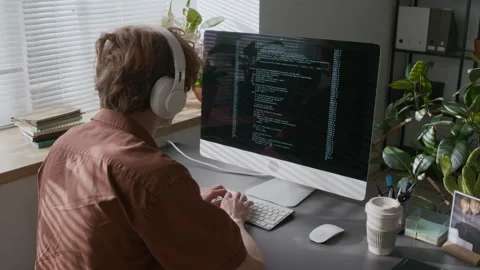 Young Programmer Putting on Headphones and Writing Code on Computer Stock Footage 299212210