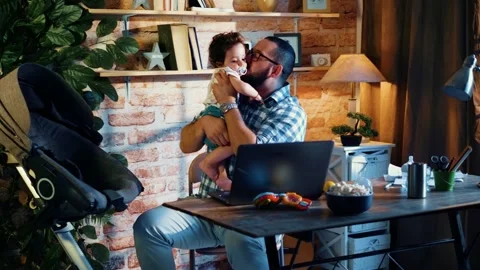 Young programmer sits at a laptop and plays with a small baby Stock-Footage 156795951