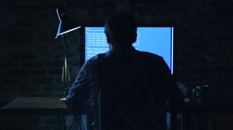 Young programmer sitting in front of a monitor at night and working on a code Stock Footage 57230157