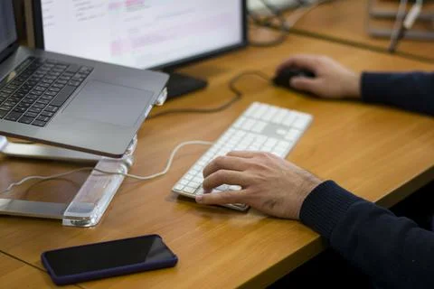 Young programmer typing on a freestanding white keyboard on a wooden table in Stock Photos