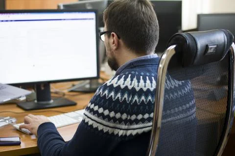 Young programmer typing on a freestanding white keyboard on a wooden table in Stock Photos