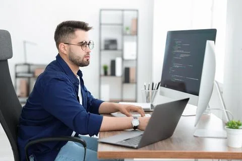 Young programmer working at desk in office Foto stock