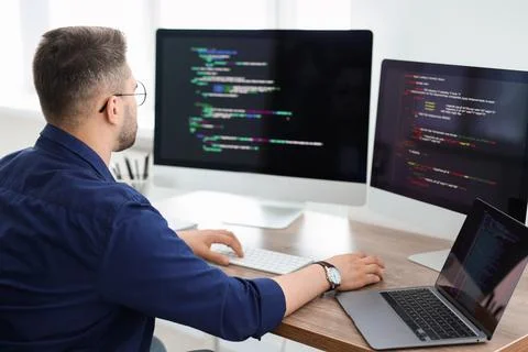 Young programmer working at desk in office, back view Stock Photos