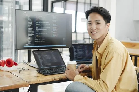 Young programmer working on desktop PC in office of software company. Stock Photos