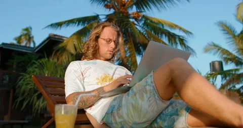 A young programmer working with a laptop lying near the ocean Stock Footage 105730866