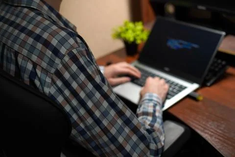 A young programmer works with his hands on a laptop with a green screen in .. Fotos de archivo
