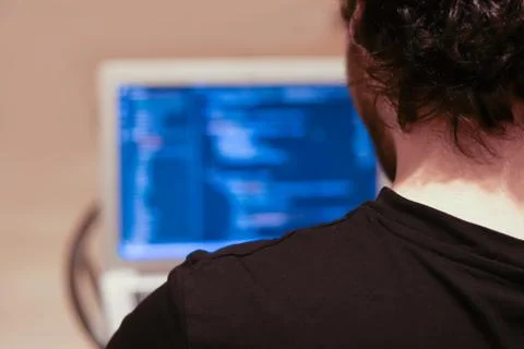 Young programmer writes code in a programming language on a laptop. The view  Stock Photos