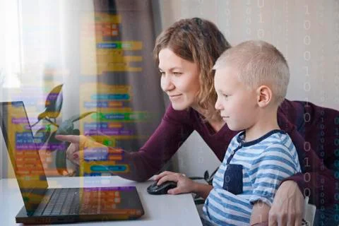 Young programmer writing code on a computer together with his mom or teacher Stock Photos