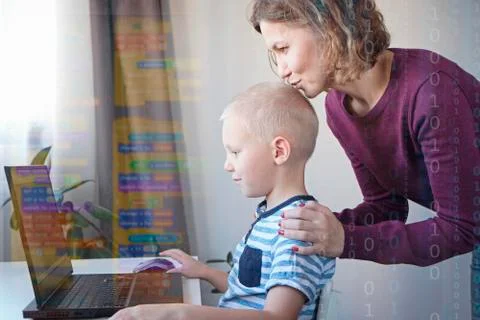 Young programmer writing code on a computer together with his mom or teacher Stock Photos