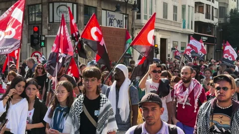 Young protesters march with CGT flags and ceasefire signs in Valencia Stock Footage 336874772