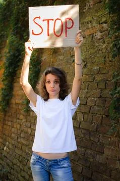 Young protesting woman in white shirt and jeans holds protest sign broadsheet Stock Photos