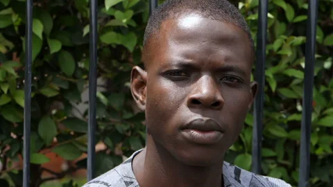 Young proud man looking at camera with the grating of the gate in the background Stock Footage 136543400