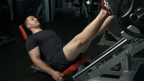 A young pumped-up athlete does another leg exercise in the gym in preparation Stock Footage 135306439