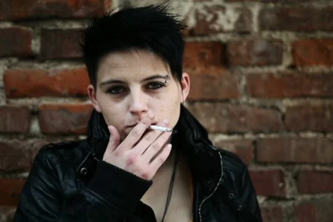 Young punk girl smoking cigarette by the brick wall, steadicam shot NTSC Stock Footage