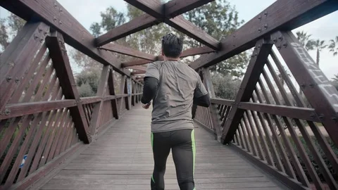 Young purposeful man running away to the city beach on a wooden bridge in the Stock Footage 104489368