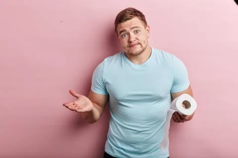Young puzzled man holding a single roll of toilet paper Stock Photos