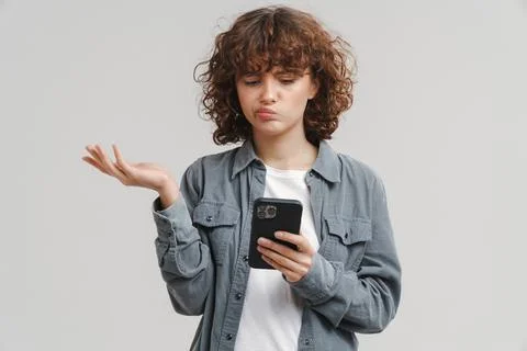 Young puzzled woman holding copyspace while using mobile phone Stock Photos