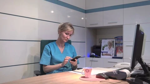 Young receptionist browsing smartphone looks to camera. Steadicam shot. 库存影片 70307063