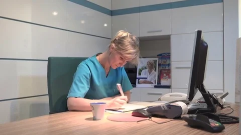 Young receptionist making notes and smiling to camera. Steadicam shot. Vidéo 70306844