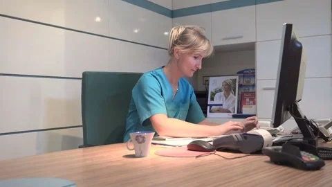 Young receptionist working on computer and smile to camera. Steadicam shot. Vídeo Stock 70306672