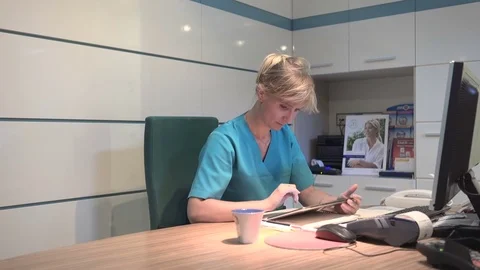Young receptionist working on tablet and drinking coffee. Steadicam shot. Vídeo Stock 70307069