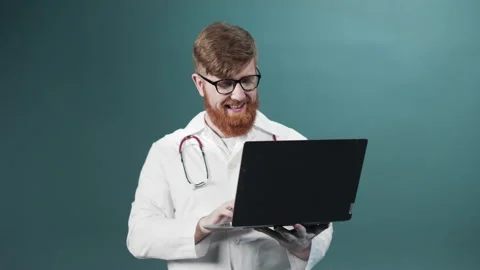 A young red bearded doctor is talking with his friend on the Internet and Stock Footage 170676033
