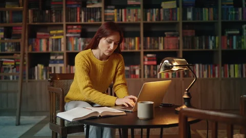 Young red-haired female scientist doing research on laptop in coffee shop Stock Footage 340267144