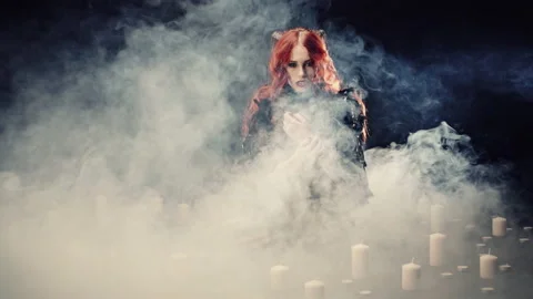 Young red-haired girl with devil horns and in black suit in dark room with smoke Video stock 135191975