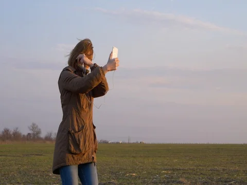 Young red-haired girl makes a selfie with a smartphone camera during wind Stock Footage 73918367