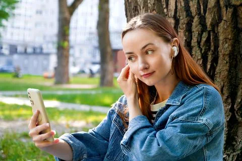 Young red haired girl using smartphone for video call. Online communication o Stock Photos