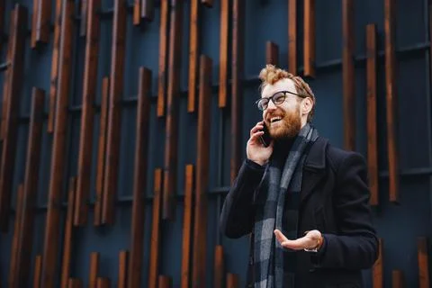 A young red-haired guy, in glasses, against the backdrop of a business center Stock Photos