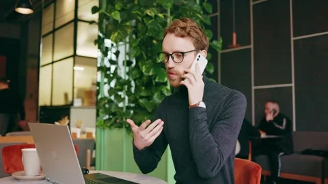 A young red-haired guy, a programmer or entrepreneur in glasses, sits in a Stock-Footage 254477767